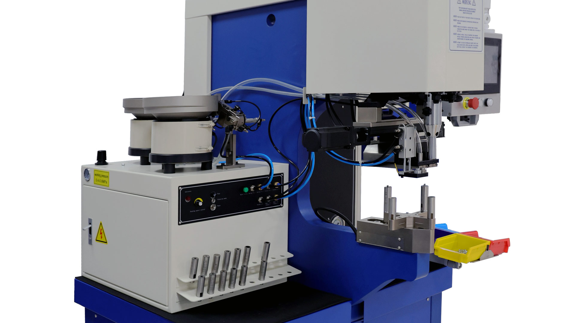 Vista en primer plano de una máquina automatizada de instalación de sujetadores con alimentadores de doble tolva, panel de control y brazo robótico. La máquina está equipada con componentes neumáticos y electrónicos, con cables azules y negros, y cuenta con bandejas para clasificar los sujetadores.