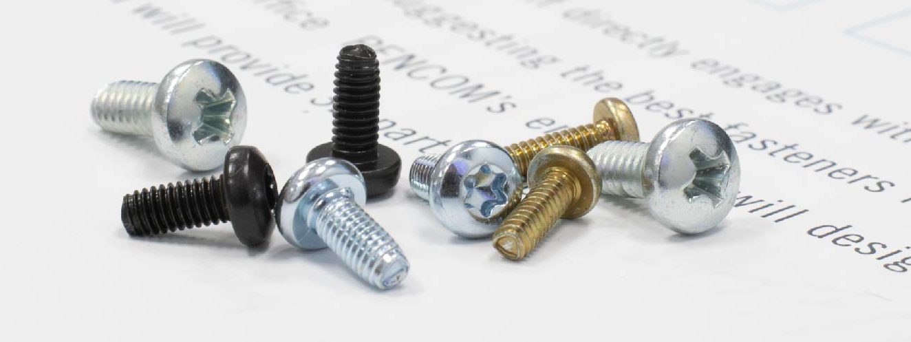 Surtido de tornillos para máquina en diferentes tamaños y acabados, incluyendo cincado, óxido negro y latón, dispuestos sobre una hoja de papel blanca con texto desenfocado.